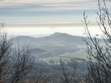 Soft outlines of hills in mist and villages in fall landscape. Unclear view to contours of hilly sides and peaks. Soft focus.