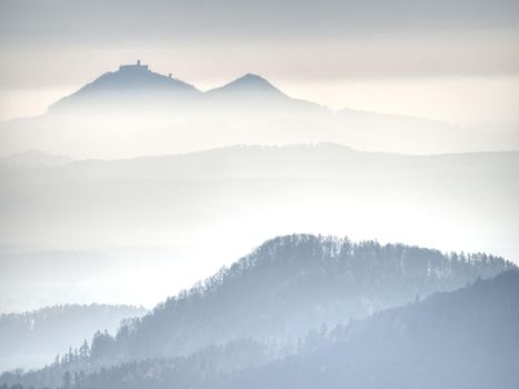 Blue mist above rounded hills in Landscape. Outline of real landscape in morning golden light.