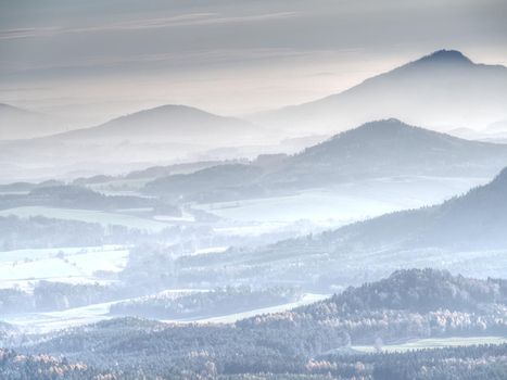 Blue mist above rounded hills in Landscape. Outline of real landscape in morning golden light.