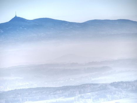 Blue mist above rounded hills in Landscape. Outline of real landscape in morning golden light.