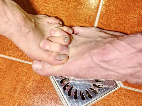 Female and male feet of together washing bodies in shower room. Feet on red tilles selective focus on toes