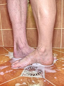 Feet of girlfriend  and boyfriend together in tilled shower stall. Modern design of bathroom.