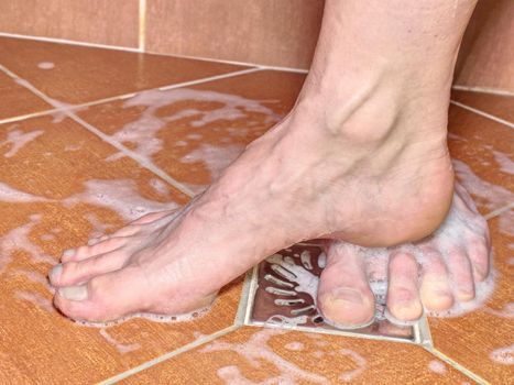 Two lovers, man and woman barefoot in shower.  Feet on red tilles selective focus on toes