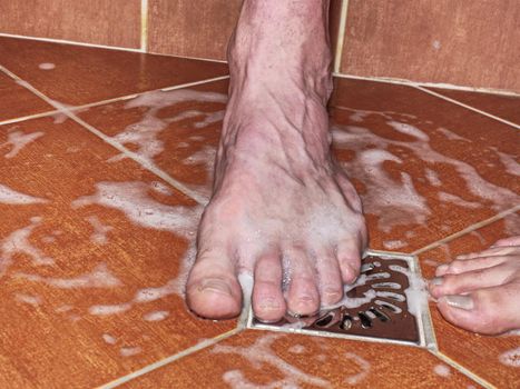 Two lovers, man and woman barefoot in shower.  Feet on red tilles selective focus on toes
