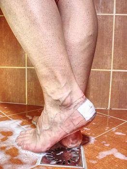 Covered cracked heels in shower.  Sticking water resistant patch on woman foot