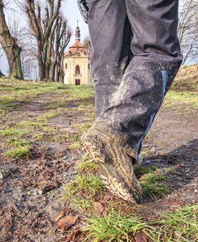 Farmer wearing muddy boots in daily business. Muddy rubber boot in horse farm area