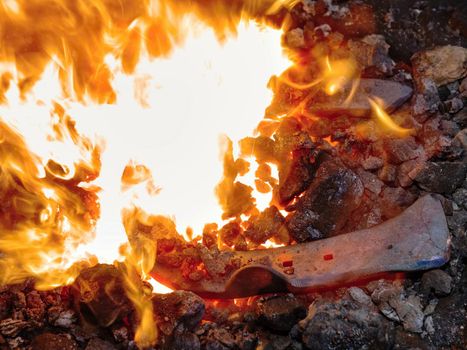 Blacksmith working hard  with iron and fire to make horseshoe