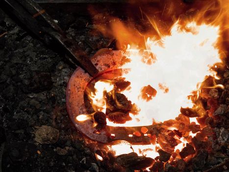 Iron bar heating in old fashioned blacksmith furnace with burning coals