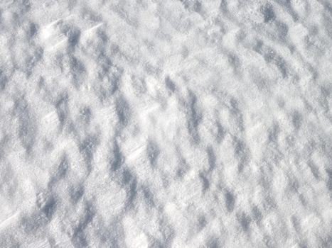 Snow with light reflections from cold winter sun. Snowflakes and shadows detail