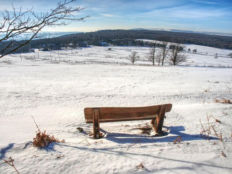 Wooden bench  on hill covered in snow with a Christmass wintery and snowy background