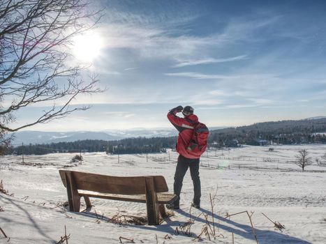 Back view of man hiker with backpack looking to landscape covered snow