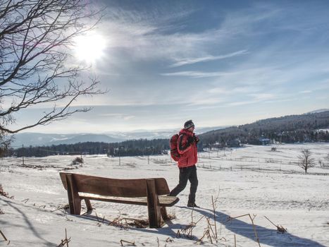 Back view of man hiker with backpack looking to landscape covered snow