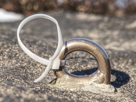 Steel bolt with plastic strap anchor eye in sandstone rock.