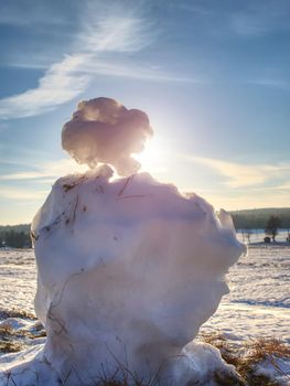 Young man walk at melt sowman in spring landscape on snow.  Tourist hiker with backpack on snowy field walking towards 