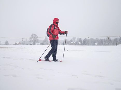 Hiker with snowshoes and technical outdoor clothing for mountain walks in snow