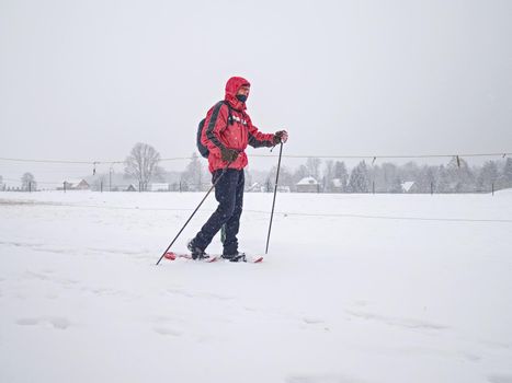 Hiker with snowshoes and technical outdoor clothing for mountain walks in snow