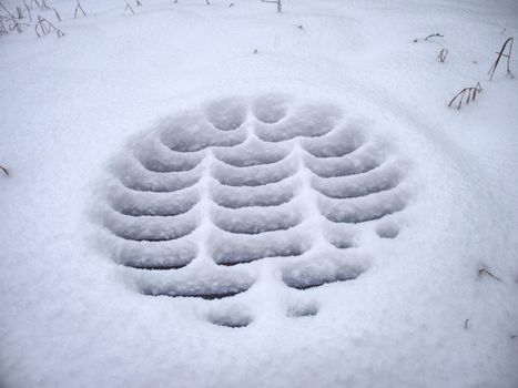 Manhole covers after snowfall covered by snow. Snow Covered Sewer enter. Pattern of snow deposits on a metal grid