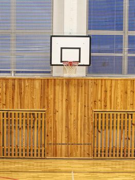 School gym with basketball board and basket.  Basketball hoop in the high school gym