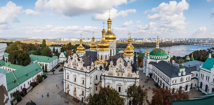 Kiev Pechersk Lavra. Cathedral of the Dormition. Kiev. Ukraine. Green and yellow autumn trees on background. Dnieper River and the panorama of Kiev in the background