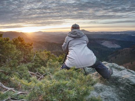 Photographer taking picture. Woman artist photo enthusiast stay with camera above valley and works. Nice view over dried trees in valley.