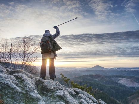 Woman reached mount peak. Girl wearing backpack and sunglasses, using trekking sticks, enjoying cloudy daybreak. Outdoor activity, tourism concept