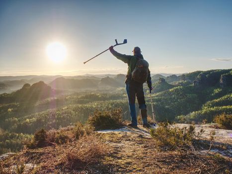 Hiker with medicine crutch achieved mountain peak. Broken leg fixed in immobilizer.  Open mountain valley bellow cliff. 