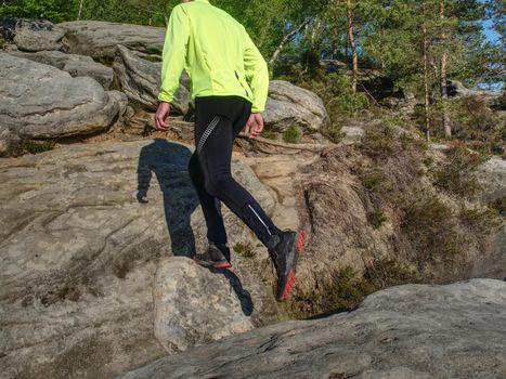 Man athlete while jumping during a trail running in the mountains. Sportsman Legs Running on the Rocky Mountain Trail.