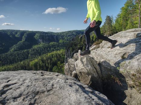Man athlete while jumping during a trail running in the mountains. Sportsman Legs Running on the Rocky Mountain Trail.