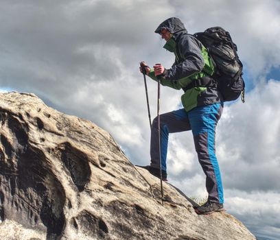 Climbing high up. Mountaineer with backpack hiking in mountains, climbing lifestyle. Man on top