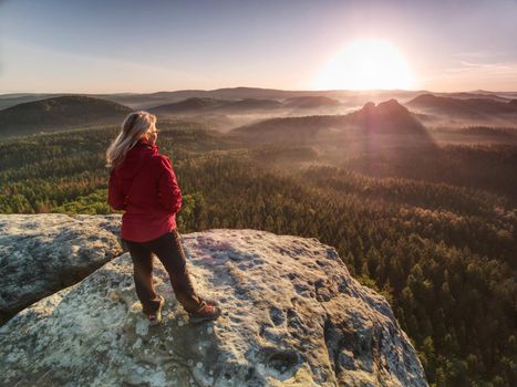 Woman with outdoor clothes  enjoying view at summit top in mountains. Traveling along mountains freedom and active lifestyle concept