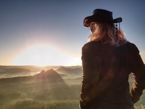 Fit body blond hair woman on the top of the high rocky mountain in the evening. Beautiful sunset autumn forests rocks and hills on the background