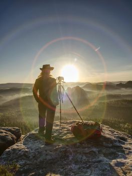 Camera in the hands of creating  girl photographer. Marvelous  art work in nature with a camera on tripod.