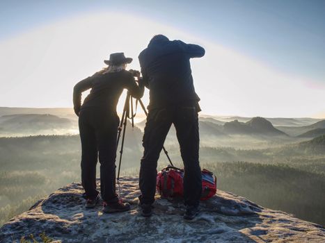 Couple tourist with photo camera at top of mountain watch sunset outdoors during a hike in pure nature