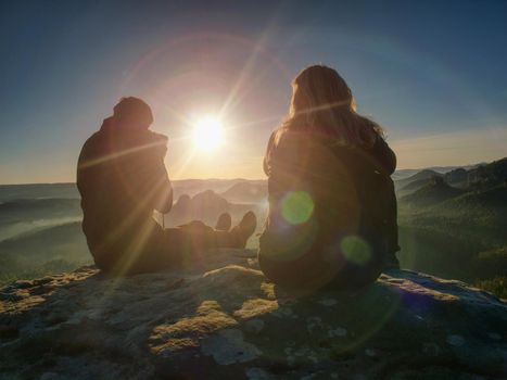 Couple tourists with tripods and cameras take pictures to the background of beautiful hills and sky. Young people in a mountain hike. Freedom and travel concept.