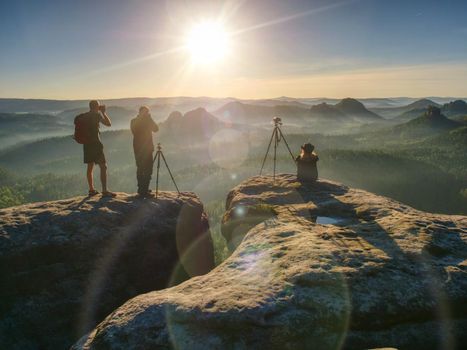 Photographers within workshop share their thoughts, stay with digital equipment together. Artists with professional equipment shooting a sunset