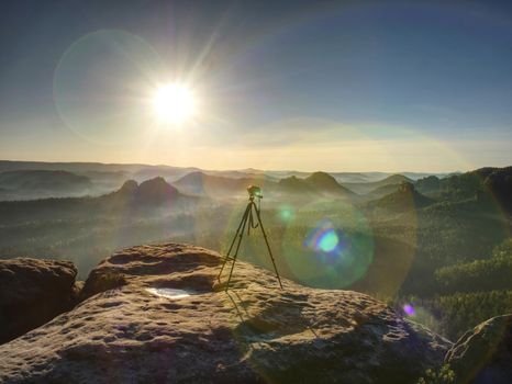 Digital photo camera with tripod  record video during sunrise in the fog, outdoors artist equipment works remote