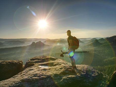 Photographer taking travel nature photography. Tall man photographer shooting with DSLR camera in sunset and clear sky with beautiful landscape in background.