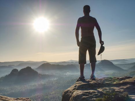 Handsome man in cowboy clothes at the edge. Man above deep gulch.