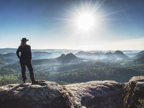 Cow girl in rocky mountains.  Happy woman tourist stay on the peak of mountain and look on the nice misty landscape