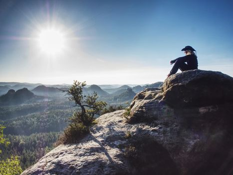 Attractive woman wearing a straw cowboy hat is sit in front of large valley, looking out across the horizon.