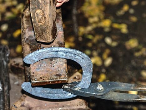 Blacksmith working on the anvil, making a horseshoe. Traditional tools for craft in workshop. Blacksmith occupation concept.