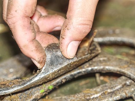 Fingers touch old brushed orthopedic horseshoes. Removed used steel horse hoof cover.