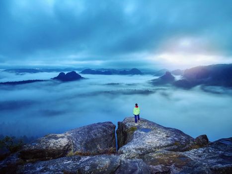 Darkness, girl and mountains. Silhouette of standing woman on the mountain peak, mountains and dark cloudy sky at night in mountains