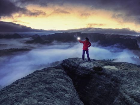 Woman bring the light on mountain to give light to whole world in darkess. Silhouette of woman standing against misty night landscape