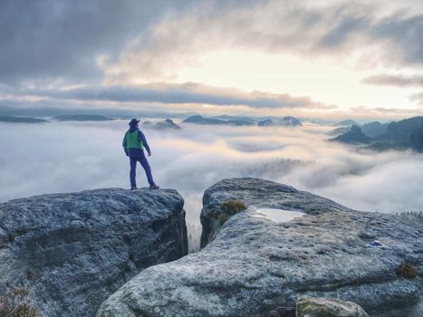 Hike in the autumn mountains. Man stay above heavy mist in deep valley.  Hike in pure nature  is the popular recreation activity in all of the world.