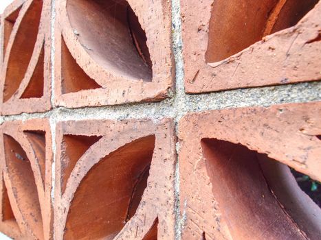 Perforated red terracotta bricks in garden wall fence. Building construction concept