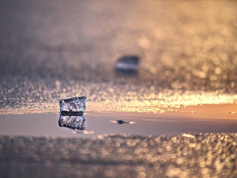 Shining icebergs and ice floes, ice clefts reflected rays in the smooth water surface. Drift ice in lagoon.