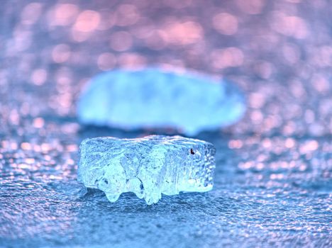 Ice shard and small cracked ice pieces on melring glacier. Icy fragments are melting on flow ice and dark laggon water