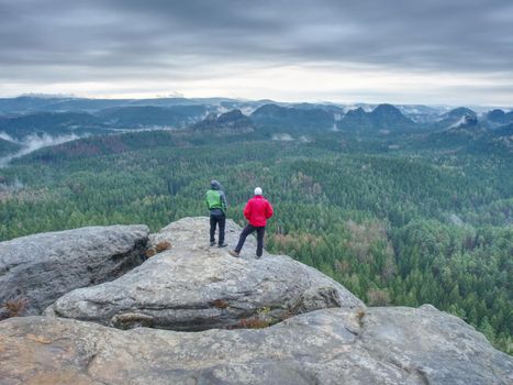 Friends in nature. Tourists travelers with backpacks in the rocks watch the landscape in mist. Poor visibility