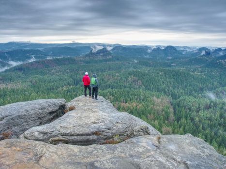 Friends in nature. Tourists travelers with backpacks in the rocks watch the landscape in mist. Poor visibility